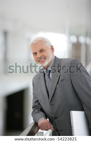 Portrait of senior man smiling in suit with a laptop computer