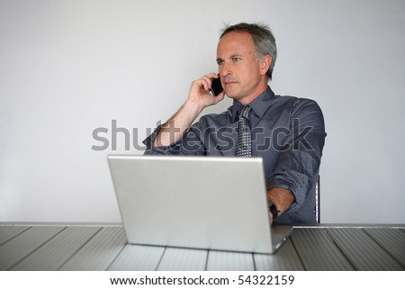 Portrait of a man in suit in front of a laptop computer with a phone