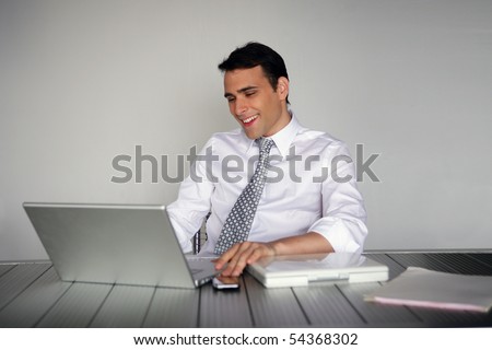 Portrait of a smiling man in suit in front of a laptop computer
