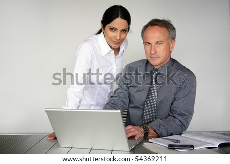 Portrait of a woman and a man in suit in front of a laptop computer