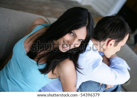 Portrait of a young couple smiling back to back on a sofa