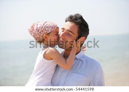 Portrait of a little girl kissing a man on the cheek