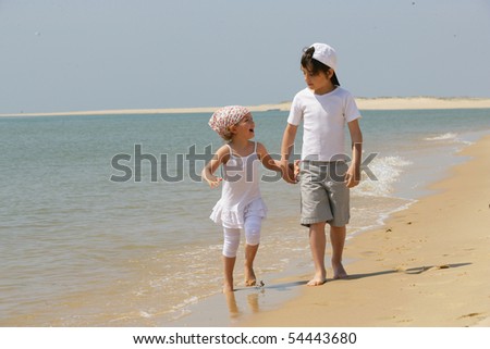 Little girl and little boy having a walk by the edge of the sea