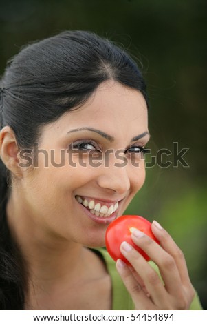 Portrait of a young woman smiling with a tomato in her hand