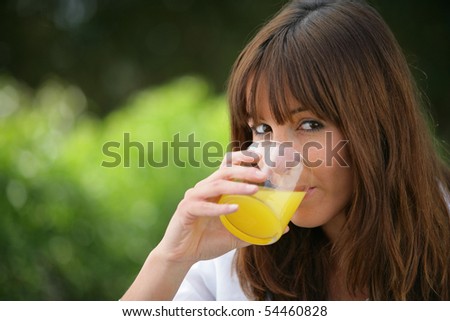 Portrait of a young woman drinking a glass of orange juice