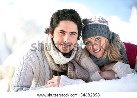 Portrait of a young couple stretched out on the snow