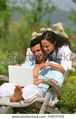 Portrait of a man on a deck chair and a woman in front of a laptop computer