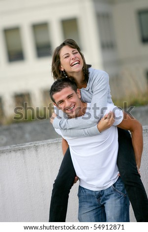 Portrait of a smiling young man carrying a young woman