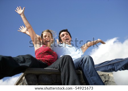 Portrait of a young woman and a young man with arms up