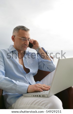 Portrait of a man phoning in front of a laptop computer