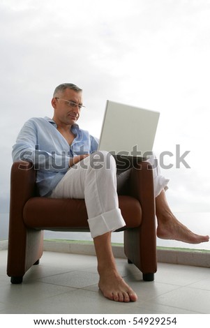 Portrait of a man sitting in an armchair with a laptop computer
