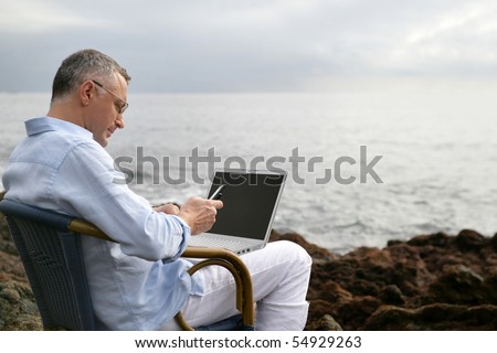 Portrait of a man sitting with a laptop computer face to the sea