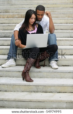 Portrait of a young couple sitting on steps with a laptop computer