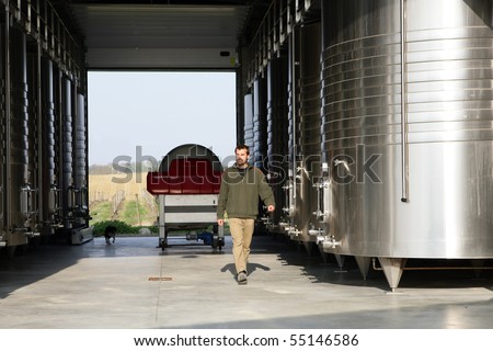 Wine producer walking next to wine tanks