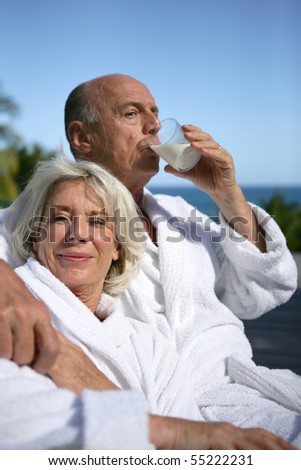 Portrait of a senior woman in bathrobe and a senior man in bathrobe drinking a glass of milk