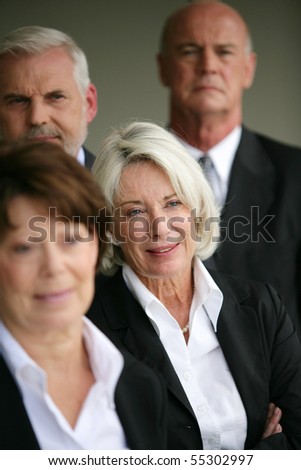 Portrait of a senior woman in suit next to senior people