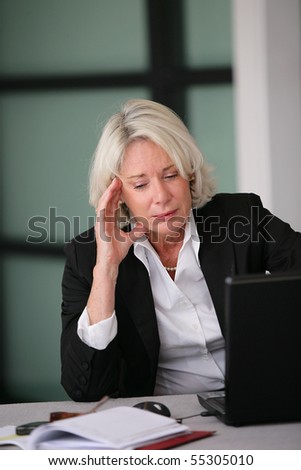 Portrait of a senior woman in suit in front of a laptop computer