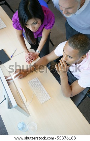 Men and a young woman in front of a desktop computer