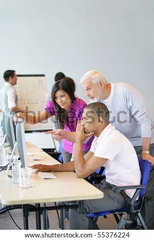 Portrait of a young woman and men in front of a desktop computer