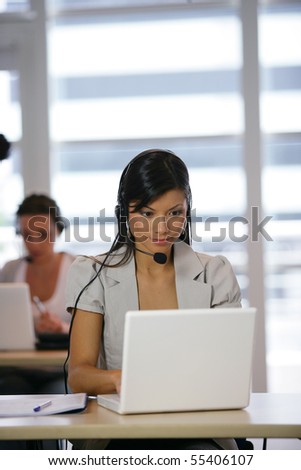 Portrait of a young woman with a headset in front of a laptop computer