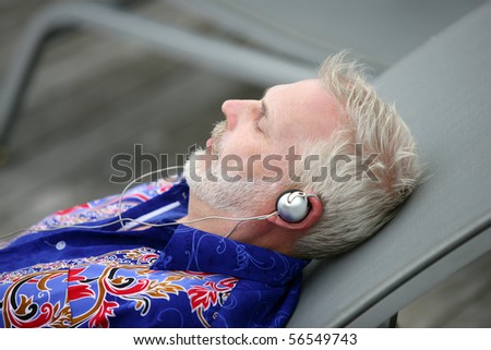 Elderly man laid on a deck chair listening to music