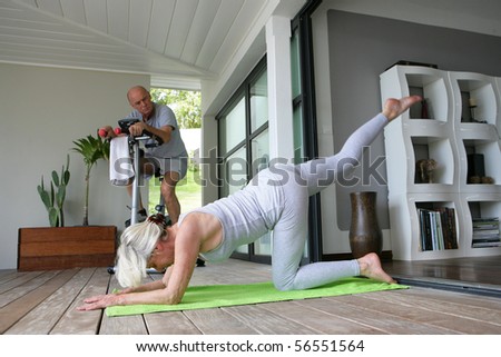 Elderly woman doing fitness next to a man doing bike