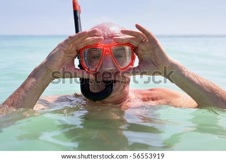 Elderly man bathing in the sea with mask and snorkel