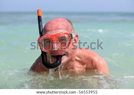 Elderly man bathing in the sea with mask and snorkel