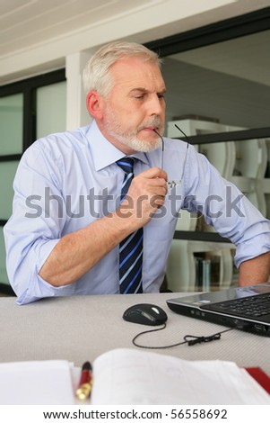 Senior man sitting at a desk in front of a laptop computer