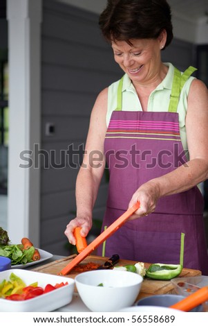 Senior woman with an apron grating carrots