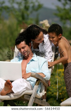Smiling woman with a boy and a man sitting in front of a laptop computer