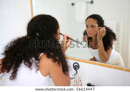 Young woman making up in a bathroom