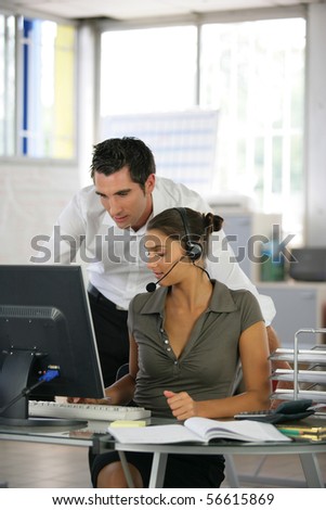 Man at a computer near a woman with a headset