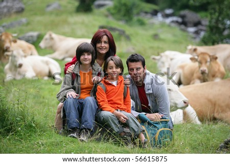 Portrait of a smiling family in the countryside in front of a herd of cows