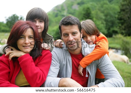 Portrait of a smiling family in the countryside in front of a herd of cows