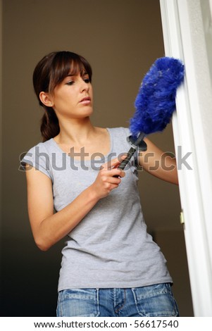 Portrait of a young woman dusting a curtain