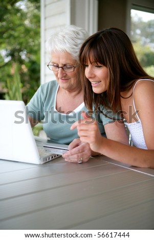 Portrait of a young woman and a senior woman with a credit card in front of a laptop computer