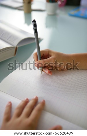Closeup of the hands of a little boy writing on a notebook