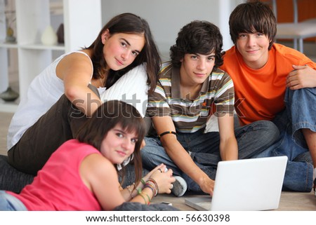 Group of teenagers sitting on the floor in front of a laptop computer