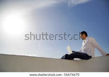 Young man sitting in front of a laptop computer face to the sea
