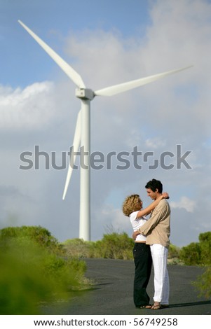 Young couple standing in front of a wind turbine