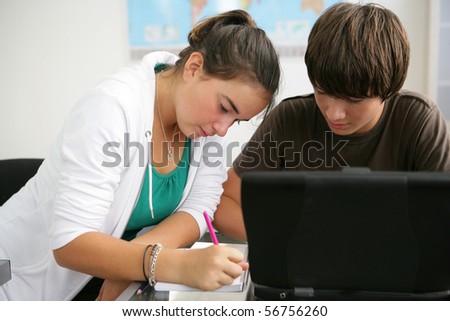 Portrait of a boy and a girl in front of a laptop computer in a classroom