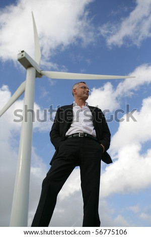 Man in suit in front of a wind turbine looking away