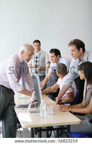 Men and women sitting at a desk in front of a desktop computer
