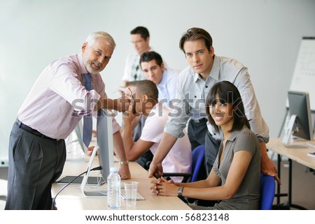 Men and women sitting at a desk in front of a desktop computer