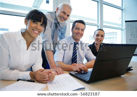 Smiling business people sitting at a desk in front of a laptop computer
