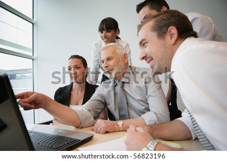 Smiling business people sitting at a desk in front of a laptop computer