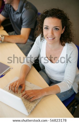 Portrait of a smiling young woman in front of a laptop computer
