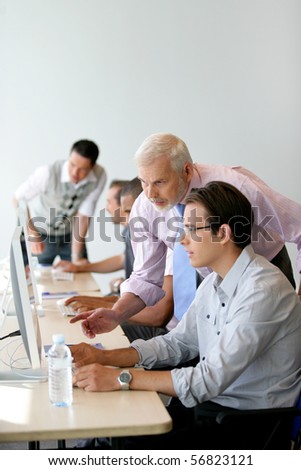 Senior man and young man in front of a desktop computer