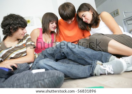 Portrait of teenagers sitting on the floor with a portable game console